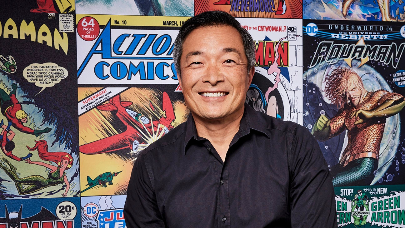 Jim Lee vor einem Hintergrund voller Comics, auc Action Comics und Aquaman